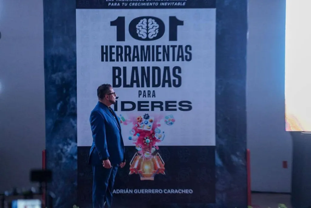 Dr. Adrián Guerrero Caracheo en el escenario junto al cartel del libro